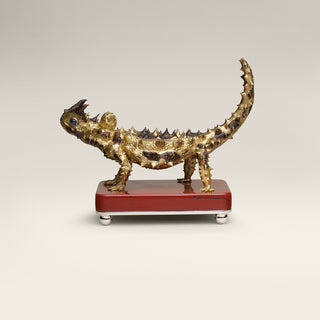 Sterling silver Thorny Devil sculpture with yellow gold plating, copper detailing and sapphire eyes, mounted on a red jasper stone base.