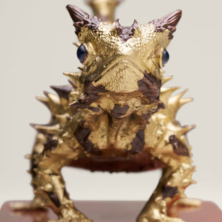 Sterling silver Thorny Devil sculpture with yellow gold plating, copper detailing and sapphire eyes, mounted on a red jasper stone base.